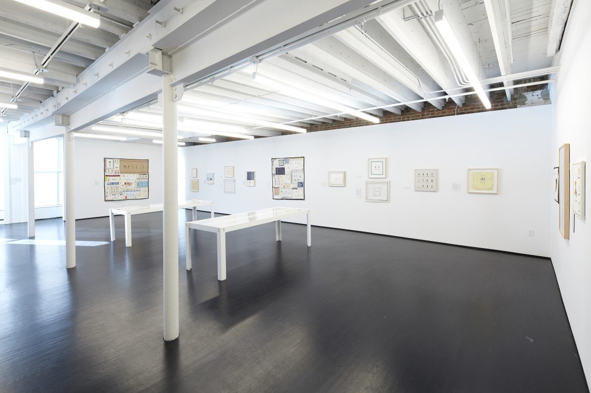View of a room with two tables and framed artworks on the walls.