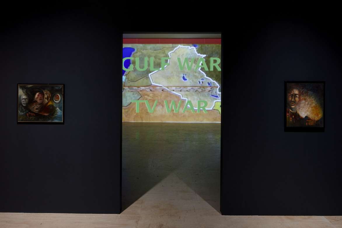 View of two black walls with doorway in the center. Through the doorway is a projects images of a map with the words 