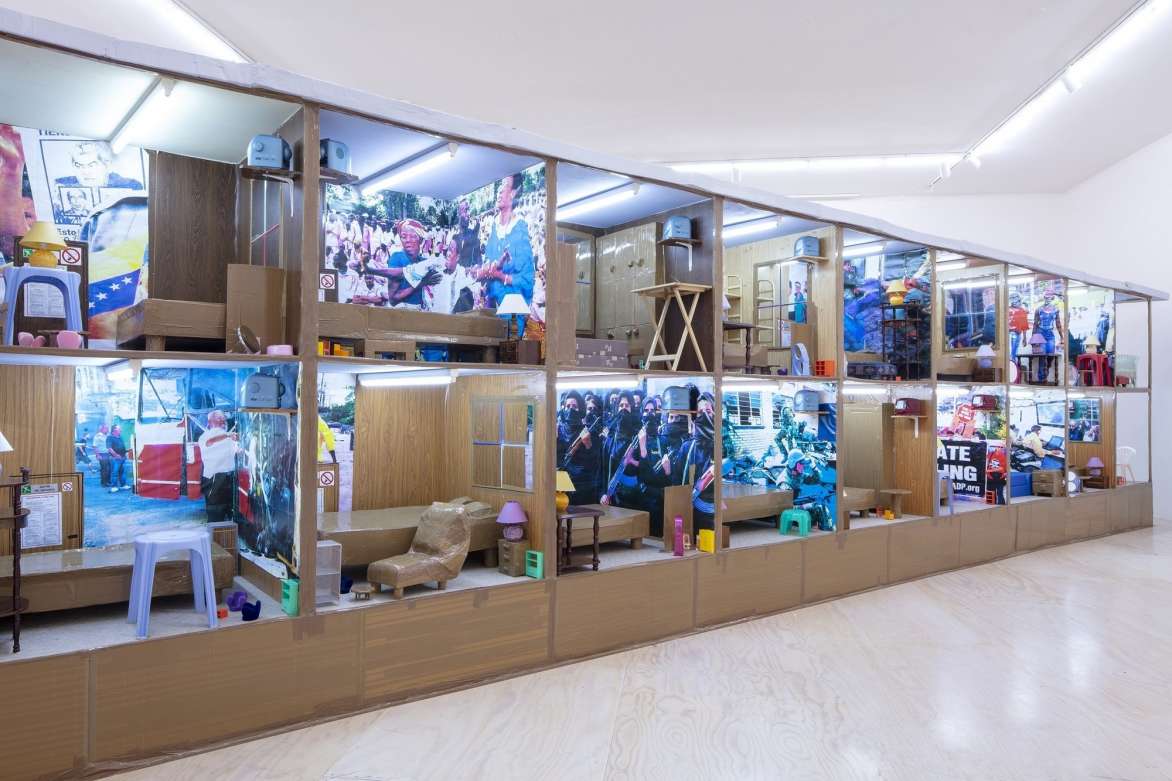 A wall of two rows of compartments outfitted with domestic interiors.