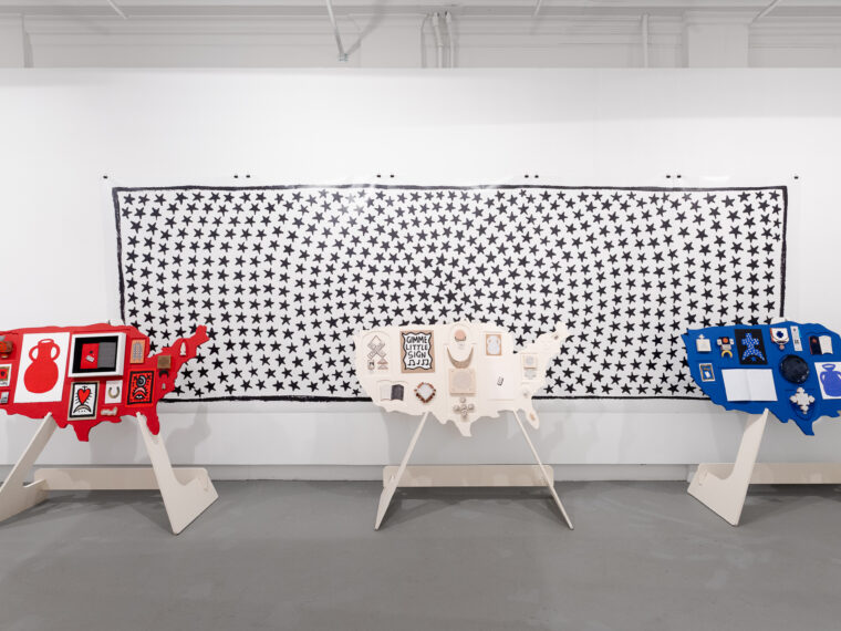 Julia Arredondo, Talismans Across the Nation, (Red, White, and Blue), Mixed media, MDF cutouts and stands, 2020 – 2025. (Background: Star Vortex Wall, 2025, five digitally printed adhesive vinyl sheets). Photo by Joel Tsui.